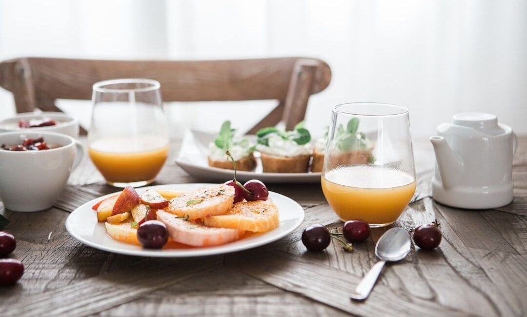 Frukost dukad i mjukt fönsterljus med juice, frukt och bröd