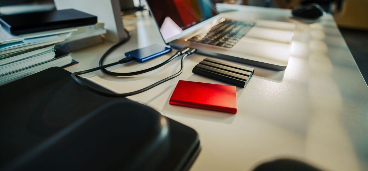 Laptop, extern hårddisk och kablar på ett skrivbord